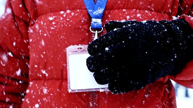 Person in Red Winter Jacket with Blank ID Badge and Black Glove in Snow