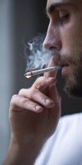 Fototapeta premium Young caucasian male smoking cigarette close-up with focus on smoke and expression