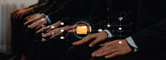 Businessmen sit in a professional setting, showcasing hands resting together while a sleek digital interface highlights data, security, and collaboration themes. Trope