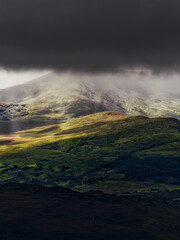 Mountain range in Killarney National Park shrouded in mist under a dark sky.