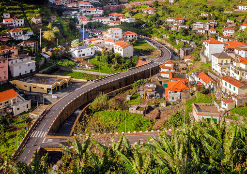 The aerial view of abstract madeirin village with beautiful residential houses and nicely curved road along with mountain creek. Madeira, Portugal