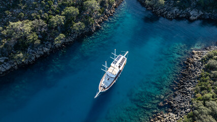 Tranquil Voyage: A majestic sailing vessel navigates a serene, azure waterway, embraced by the embrace of a lush, verdant landscape, inviting exploration and escape.