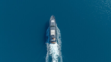 Fototapeta premium Seafaring Voyage: An overhead perspective of a sleek vessel slicing through serene blue waters, creating a wake that traces its path. 