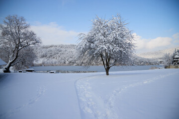 Fototapeta premium A calm winter landscape on the lake in the village of Semigorsky in the mountains of the city of Novorossiysk, snow-covered shores, the silence of nature and a cold atmosphere.