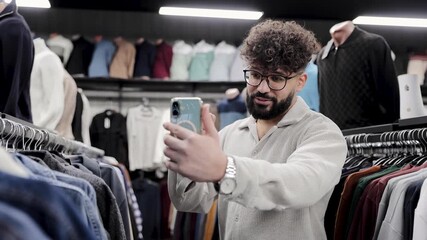 Man creating digital content for social media, showcasing new clothing items and fashion trends in a retail boutique