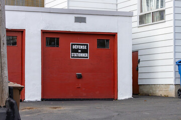 Naklejka premium Canada, Quebec, 08 November 2025 : Red garage doors with French no parking sign above entrance area