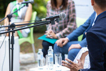 Business round table discussion with microphones, corporate panel speakers, professional conference networking event, outdoor seminar