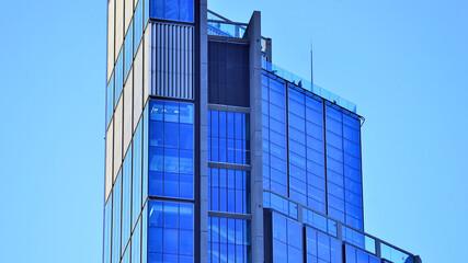 Obraz premium A modern tall building made of steel and glass, housing offices and financial institutions. Glass wall on the facade of the building.