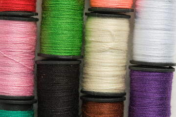 Background of multicolored spools of thread on white background in closeup.