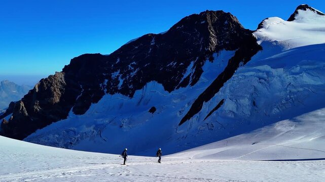 People trekking to Capanna Margherita, the highest mountain hut in Europe, located on Monte Rosa in the Italian Alps. Surrounded by glaciers, snowy peaks and alpine landscape. Italy