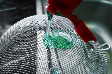 Strainer stainless steel with diswashing liquid pouring on it.