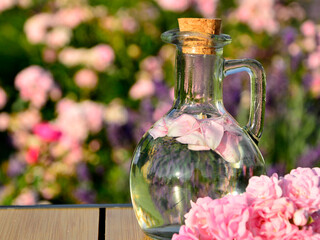 woda różana w szkalnej butelce z korkiem, woda aromatyzowana płatkami róży w butelce, rose water in a glass bottle, water flavored with rose petals in a bottle, Rose water in a glass bottle © kateej