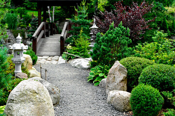 żwirowa ściezka otoczona roślinami i drewniany most w ogrodzie japońskim, designer garden, a gravel path surrounded by plants and wooden bridges in a Japanese garden, Zen garden © kateej