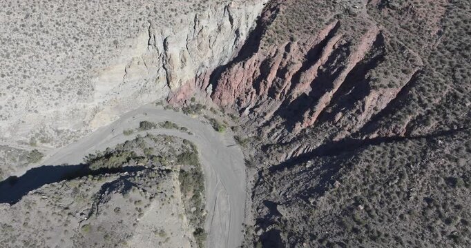 Drone aerial over Tabernas Desert canyon in Almeria Spain, winding dry riverbed through rugged badlands and eroded cliffs, cinematic arid valley landscape establishing shot