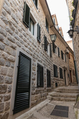 Obraz premium A sunlit stone street winds between historic buildings with dark shutters