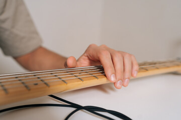 Close-up cropped shot of unrecognizable musician plucking and adjusting bass guitar strings,...