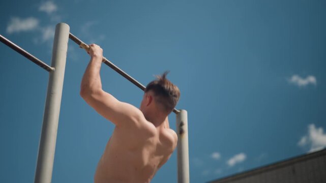 outdoor pullup exercise, man executing outdoor pullups, athletic individual doing repeated pullups in outdoor setting, focused athlete engaging muscles with pullups against sky outdoors