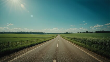 Wide Open Road Stretches Ahead Under Blue Sky and Bright Sun in Rural Area During Daytime