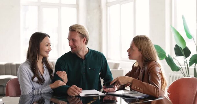 Couple signing mortgage document or rental agreement during meeting with professional bank advisor or real estate agent, shaking hands, feel happy, celebrating successful deal. Services and contracts