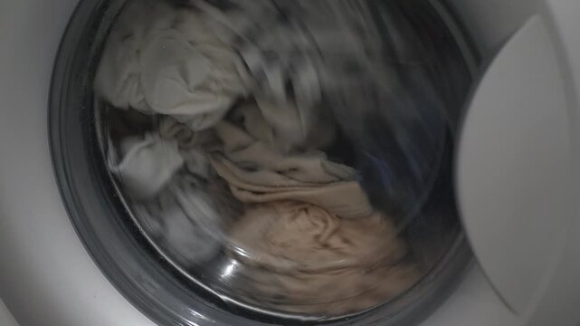 Modern washer spins clothes with soap bubbles, clothes tumbling inside washing machine, Fabrics dance within sleek washing device