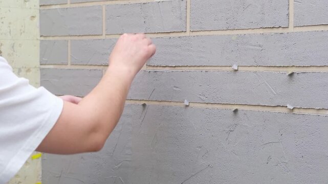 Women's hands apply putty to a wall for decorative brickwork