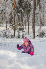 Happy child in winter park reaching hand towards camera while playing in snow on sunny day