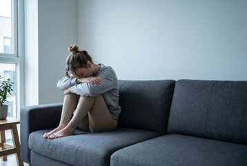 Depressed Woman Sitting Alone on Sofa in Minimal Living Room