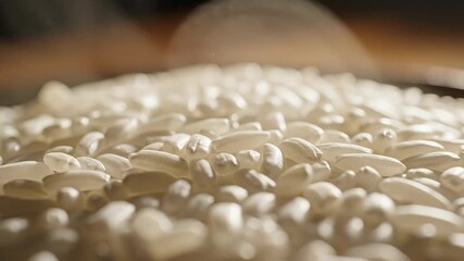 Closeup view of pristine white uncooked rice grains scattered on a surface showcasing their natural texture and readiness for culinary preparation a fundamental staple food for global cuisines and he.