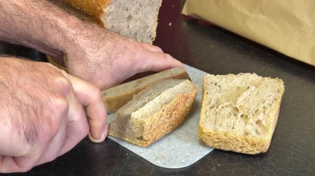 Slicing Wholegrain Bread Cri On Slice For Bruschetta. Cutting Sourdough Bread On Kitchen. Making Morning Toast Breakfast.Fresh Crisp Sourdough Bread On Table. Cutting French Multigrain Bread For Toast