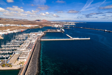 Aerial view of Port of Arrecife in Lanzarote shows breakwaters, sailboats, cranes, ferries, and...