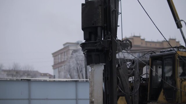 Pile driving rig installing concrete foundation pile in winter