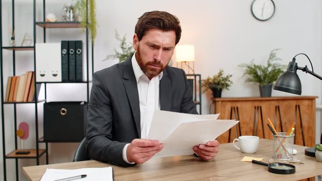 Middle-aged businessman at home office finds errors and crumples report exhales hard and calms. Freelancer guy at table opens new document edits lines fixes text and continues work with focus again.