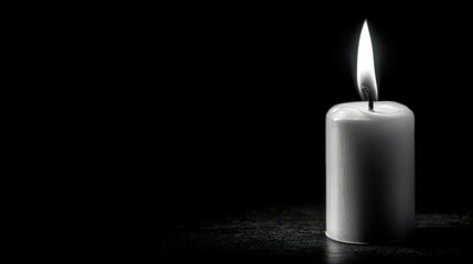 Candle lit against dark backdrop Space for your text Monochrome image symbolizing loss or sorrow