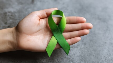 Hand holding green ribbon for awareness of liver gallbladder bile duct cervical kidney cancers and lymphoma related to healthcare and world cancer day