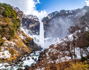 A majestic waterfall cascades down a rocky cliff, surrounded by snowy slopes and bare trees under a cloudy sky