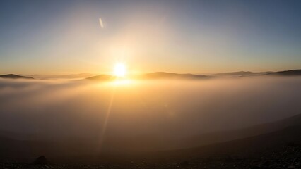 Breathtaking sunrise over a thick layer of fog in a mountain landscape, with the sun's rays illuminating the mist