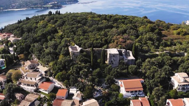 Aerial drone view of Kassiopi, coast sea village in northeast coast of Corfu island, Ionian Islands, Kerkyra, Greece in a summer sunny day, with marina, town, beach and castle, Greek landscape