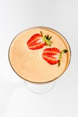 Fresh strawberry smoothie served in a clear glass with two strawberry slices on top
