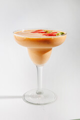 Delicious fruit smoothie served in a clear glass with fresh toppings of sliced strawberries and mint