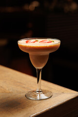 Refreshing fruit cocktail in a stylish glass served on a wooden table in a dining setting