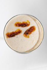 Enjoy a creamy drink topped with caramel and spices in a clear glass on a simple white background