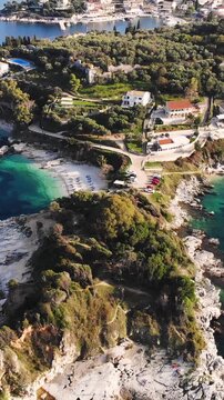 Aerial drone view of Kassiopi, coast sea village in northeast coast of Corfu island, Ionian Islands, Kerkyra, Greece in a summer sunny day, with marina, town, beach and castle, Greek landscape