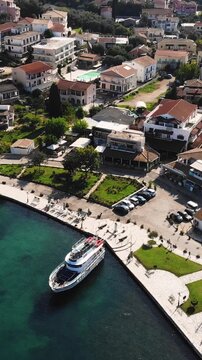 Aerial drone view of Kassiopi, coast sea village in northeast coast of Corfu island, Ionian Islands, Kerkyra, Greece in a summer sunny day, with marina, town, beach and castle, Greek landscape