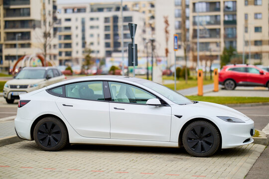 Modern white sedan parked in urban area with contemporary architecture. December 12, 2025 Brasov Romania