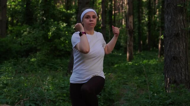 A woman exercises outdoors in a forest setting on a sunny day to improve fitness and health