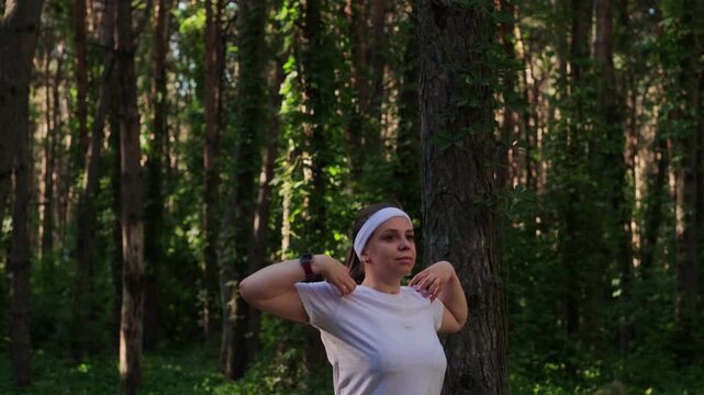 A woman exercises outdoors in a forest setting on a sunny day to improve fitness and health