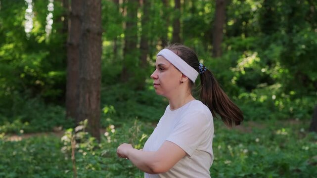 A woman exercises outdoors in a forest setting on a sunny day to improve fitness and health
