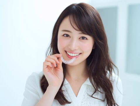 マウスピース矯正を手に取って笑顔を見せる女性の歯科医療イメージ