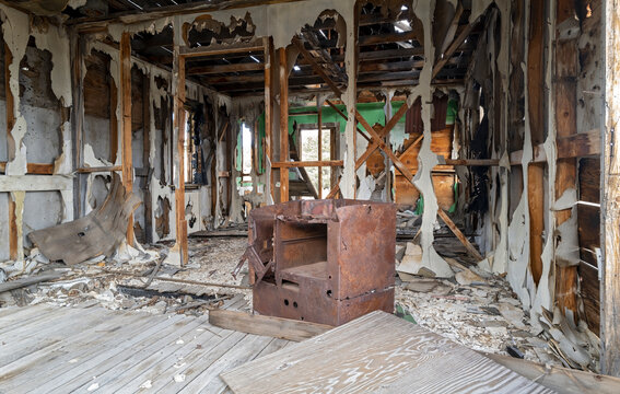 A rusty stove sits in the middle of the floor of a shack at an a