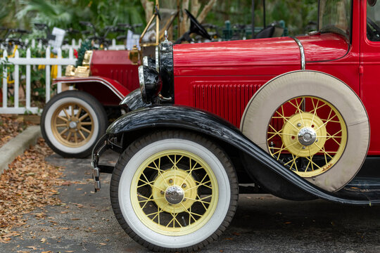 Orlando, Florida, US- January 1, 2026: Two vintage red Ford Model T trucks. The tire rims are painted bright yellow with whitewall Firestone vintage tires. The antique wheels are gum-dipped.